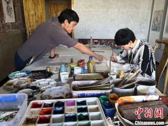 圖為2020年8月下旬，敦煌“80后”畫家張杰龍(左)在為云南麗江“學(xué)生”莫北講解敦煌壁畫的繪畫技巧?！●T志軍 攝