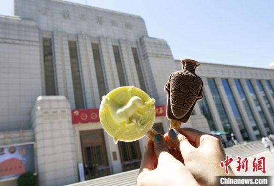 2021年7月30日，游客手拿“銅奔馬”“彩陶瓶”造型的雪糕，在甘肅省博物館前拍照打卡?！「哒?攝