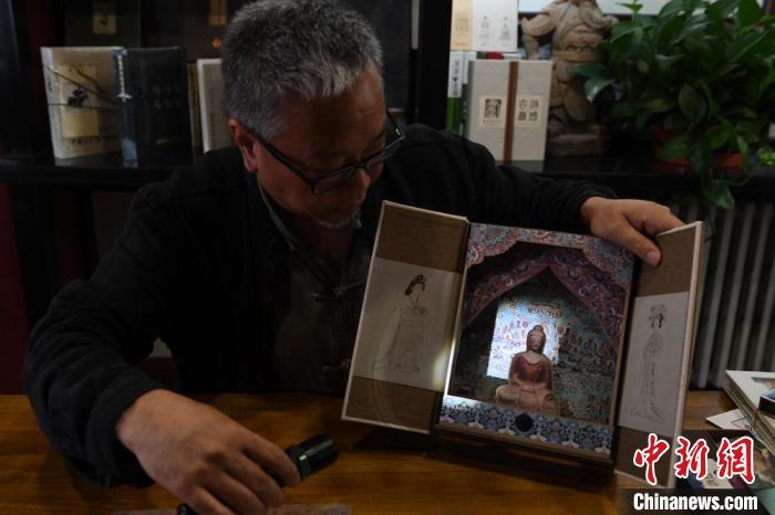 圖為讀者出版集團(tuán)讀者晉林工作室獨(dú)立出品人徐晉林，展示互動(dòng)性強(qiáng)的敦煌題材手工書。(資料圖) 楊艷敏 攝