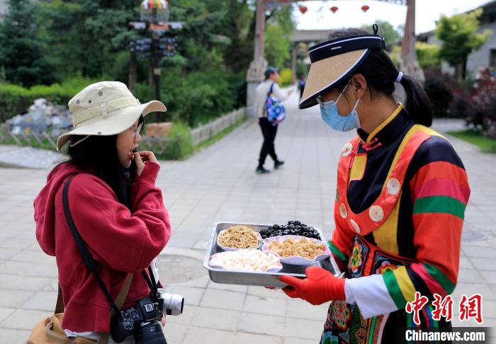 圖為身穿土族服飾的女性介紹當?shù)靥厣〕??！⊙Φ?攝