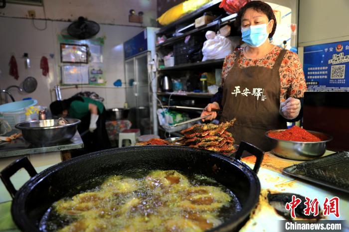 圖為平安驛·河湟民俗文化體驗(yàn)地內(nèi)的商戶炸干板魚?！⊙Φ?攝