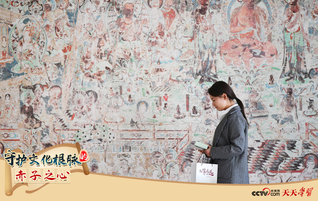 2023年4月25日，敦煌研究院文物數(shù)字化保護(hù)團(tuán)隊(duì)創(chuàng)意營(yíng)銷人員廖雪婷從一幅高保真復(fù)制壁畫前走過。