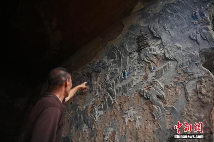 7月15日，甘肅省平?jīng)鍪袥艽h百里石窟長廊羅漢洞石窟內(nèi)，該窟文保員郭建平介紹窟內(nèi)石刻彩繪壁畫。郭建平家中三代人曾自發(fā)保護羅漢洞石窟。羅漢洞石窟遺存40余個窟龕，以北魏至清代風格為主。中新社記者 李亞龍 攝