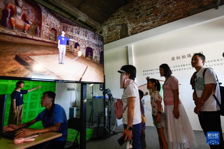 7月22日，游客體驗(yàn)“尋境敦煌——數(shù)字敦煌沉浸展”后，在虛擬演播廳拍攝一段真人與洞窟虛擬場景交互的視頻。新華社記者 郎兵兵 攝</p>
<p>