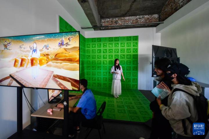 7月22日，游客體驗(yàn)“尋境敦煌——數(shù)字敦煌沉浸展”后，在虛擬演播廳拍攝一段真人與洞窟虛擬場景交互的視頻。新華社記者 郎兵兵 攝</p>
<p>